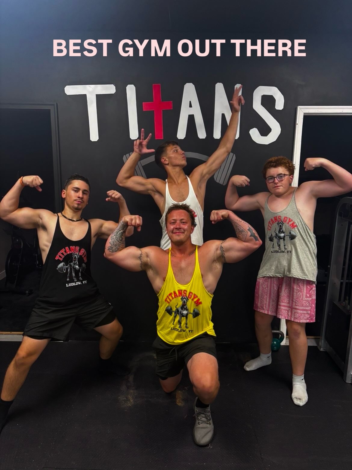 Four Titans Gym members posing together beneath the hand-painted Titans wall